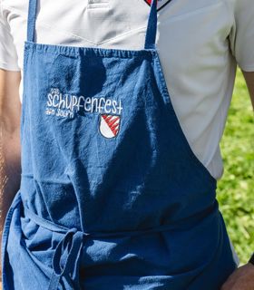 Un uomo che porta un costume tradizionale tiene in mano un calice di vino bianco e uno spuntino